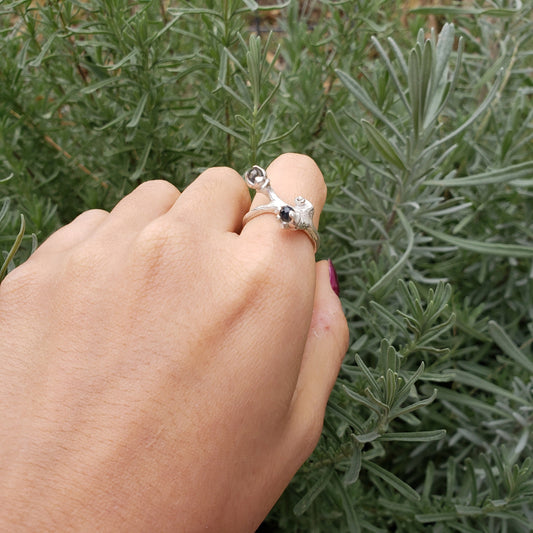 May include: A silver ring with a black stone and a twig design.